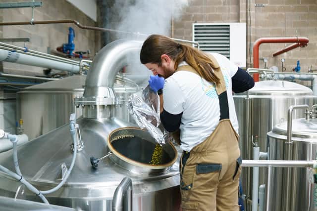 Brewer Jay Krause adding hops to a brewing tank at Cloudwater