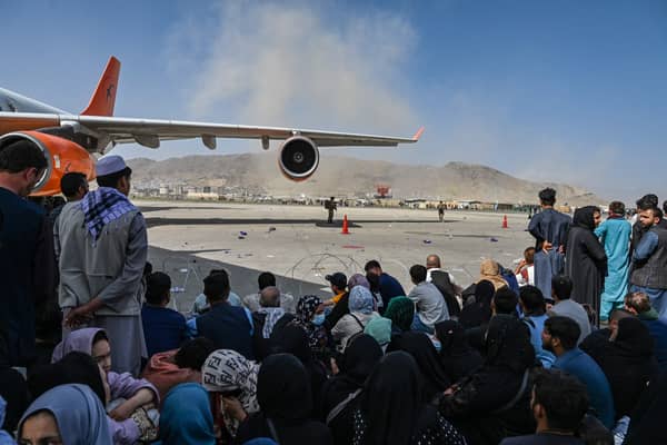 Afghan people sit as they wait to leave Kabul airport. Photo by Wakil Kohsar / AFP via Getty Images