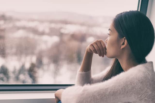 A woman stares pensively out of a window. Photo: Shutterstock