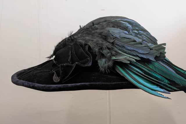 An Edwardian satin hat adorned with bird feathers
