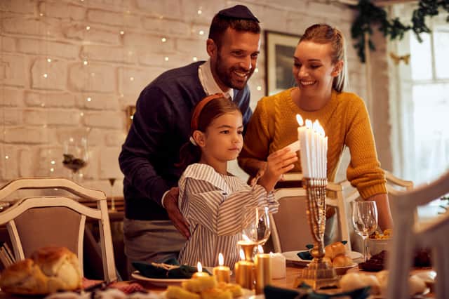 A family lightning candles in a menorah  Credit: Shutterstock