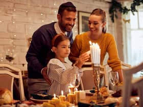 A family lightning candles in a menorah  Credit: Shutterstock