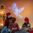 People having fun near tree indoors. Loving family watching holiday movies at home. Mother, father and daughters spending time together.