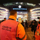 A Covid-19 spot checker is seen outside the stadium prior to the Premier League match between Manchester City and Leeds United. (Photo by Clive Brunskill/Getty Images)