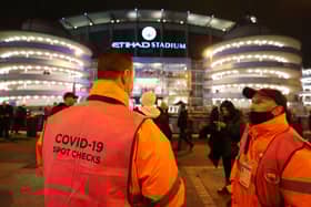 A Covid-19 spot checker is seen outside the stadium prior to the Premier League match between Manchester City and Leeds United. (Photo by Clive Brunskill/Getty Images)