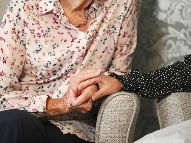 A care home resident holding hands with her daughter Credit: PA Radar