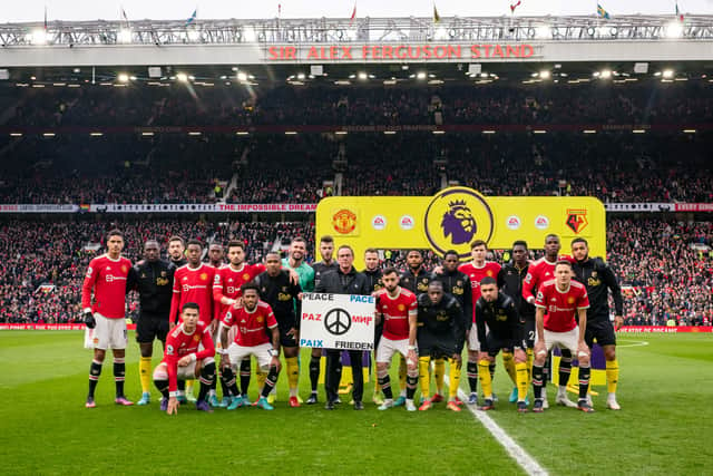 The players stand behind a peace banner at Old Trafford. Credit: Getty.