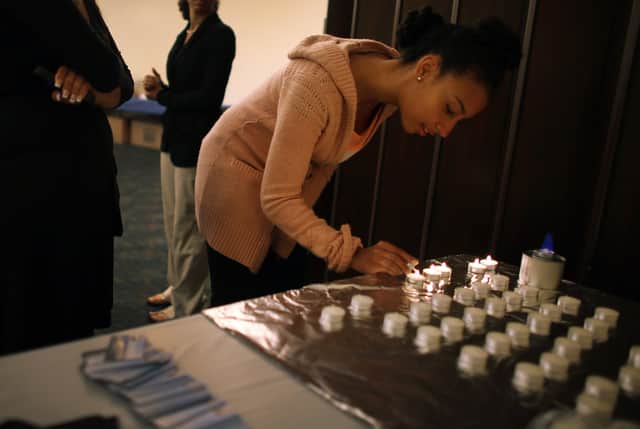 <p>A woman lights candles during a community Passover Seder Credit: Getty</p>