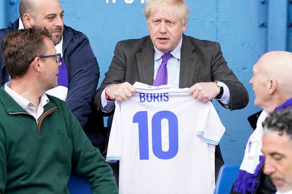 Prime minister Boris Johnson holds a jersey with his name on as he speaks to fans at Bury FC’s Gigg Lane ground. Photo: Danny Lawson/AFP via Getty Images