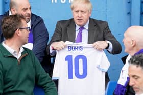 Prime minister Boris Johnson holds a jersey with his name on as he speaks to fans at Bury FC’s Gigg Lane ground. Photo: Danny Lawson/AFP via Getty Images