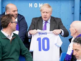 Prime minister Boris Johnson holds a jersey with his name on as he speaks to fans at Bury FC’s Gigg Lane ground. Photo: Danny Lawson/AFP via Getty Images