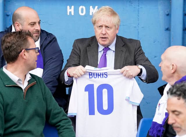 Prime minister Boris Johnson holds a jersey with his name on as he speaks to fans at Bury FC’s Gigg Lane ground. Photo: Danny Lawson/AFP via Getty Images