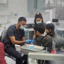 Dr Naveed Patel teaching young refugee children how to use a toothbrush