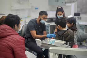 Dr Naveed Patel teaching young refugee children how to use a toothbrush