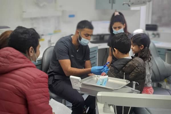Dr Naveed Patel teaching young refugee children how to use a toothbrush