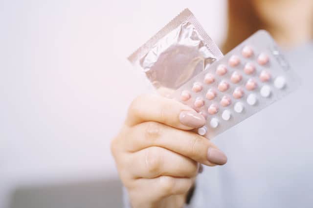 A woman with a hormonal contraceptive pill and a condom Credit: methaphum - stock.adobe.com