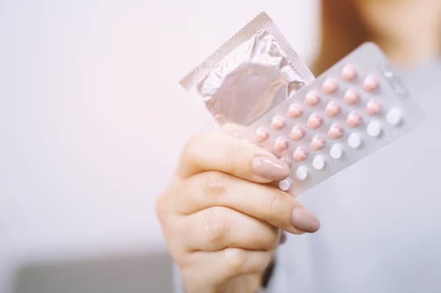 A woman with a hormonal contraceptive pill and a condom Credit: methaphum - stock.adobe.com