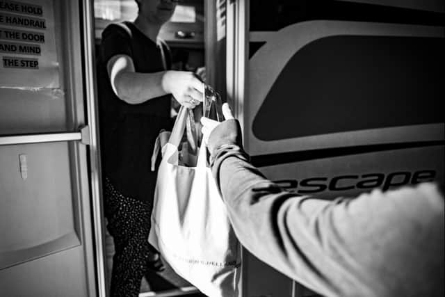 A MASH volunteer passes a bag of essential items to someone. Photo credit: Liz Henson Photography