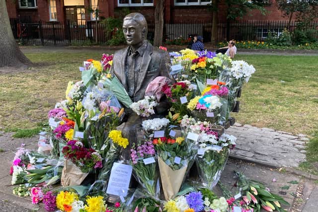 Bouquets of flowers surround the statue of Alan Turing in Sackville Gardens