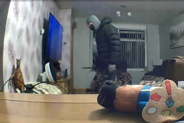 The man in a balaclava was pictured holding a knife in the family’s home in Chadderton Credit: SWNS
