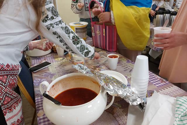 Volunteers serve cups of beetroot soup, called “borshch,” to visitors. Credit: Sofia Fedeczko/Manchester World 