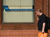 A man walks past a sign with the email address of ‘universal credit’ outside a Job Centre.