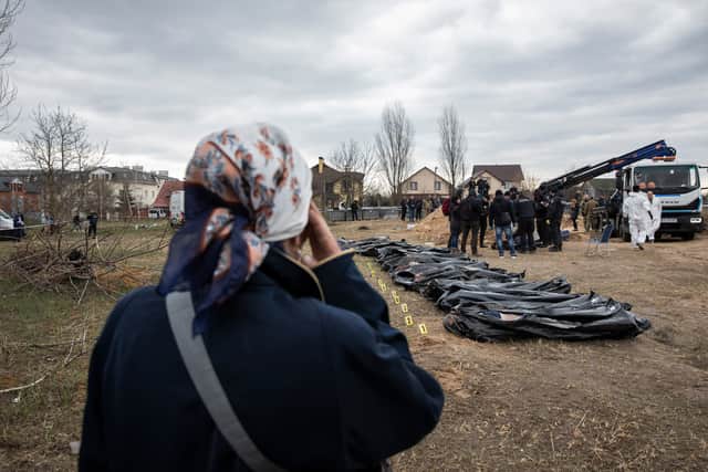 Natalia Lukyanenko (63) watches authorities excavate a mass grave in Bucha, Kyiv. Photo: Anastasia Taylor-Lind