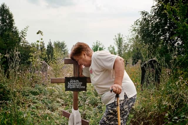 Anna Dedova, 75, at the grave of her son who accidentally killed himself with a hand grenade he found near his home in the village of Opytne last year Credit: Anastasia Taylor Lind
