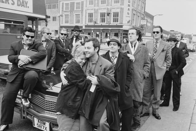 Film producer Alison Owen and her husband actor Keith Allen with cast members actors Robbie Coltrane, Adrian Edmondson, Peter Richardson, Kevin Allen and Clive Russell posing around Cadillac on the set of ‘The Supergrass’ outside Pentonville Prison on Caledonian Road in London in 1985.