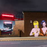 The three celebrities are beamed onto a wall at Manchester United’s Old Trafford ground
