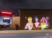 The three celebrities are beamed onto a wall at Manchester United’s Old Trafford ground