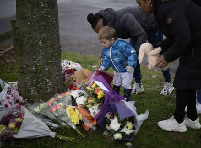 Flowers are left near the scene after three young boys died when a number of children fell through ice on a lake in Solihull. 