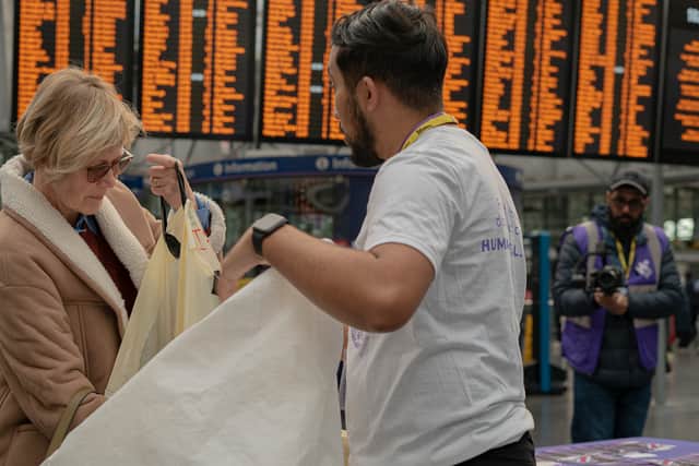 A woman donates unwanted coats to Human Appeal volunteers at Manchester Piccadilly Station. Credit: Human Appeal