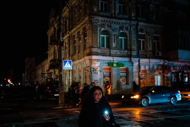A girl uses her phone as a torch to cross the street during a blackout in central Kyiv. Credit:  DIMITAR DILKOFF/AFP via Getty Images