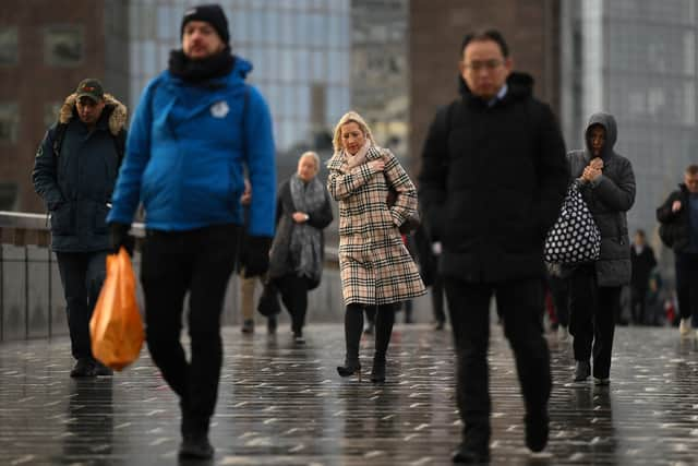 Commuters on their way to work cross London Bridge in central London.