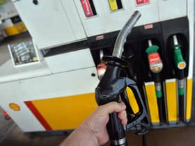 A man poses holding a petrol pump nozzle at a filling station in Birkenhead, north-west England.  (Photo credit should read PAUL ELLIS/AFP via Getty Images)