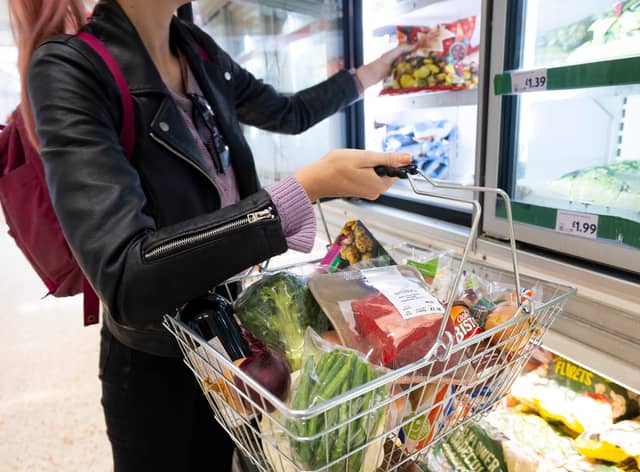 A woman holds a basket of shopping.