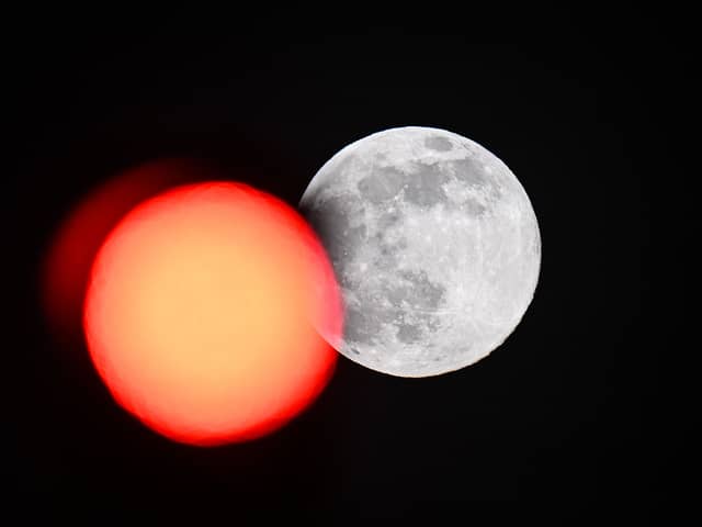 TOPSHOT - This picture taken on February 5, 2023 shows the full moon rising behind a red crossing light in Paris. (Photo by Stefano RELLANDINI / AFP) (Photo by STEFANO RELLANDINI/AFP via Getty Images)