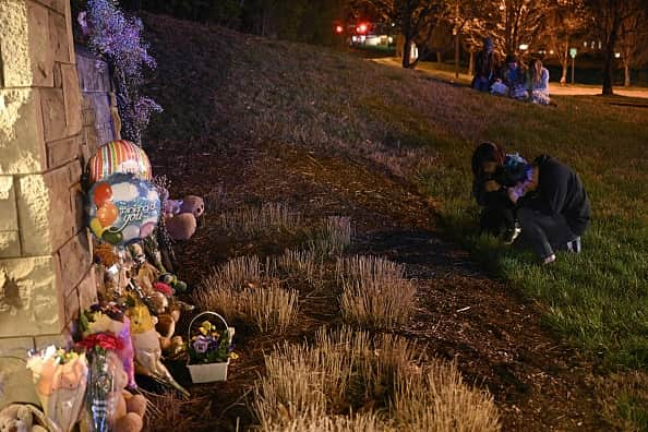 People gather at a makeshift memorial for victims outside the Covenant School building at the Covenant Presbyterian Church following a shooting, in Nashville, Tennessee, on March 27, 2023. - A heavily armed former student killed three young children and three staff in what appeared to be a carefully planned attack at a private elementary school in Nashville on Monday, before being shot dead by police. Chief of Police John Drake named the suspect as Audrey Hale, 28, who the officer later said identified as transgender. (Photo by Brendan SMIALOWSKI / AFP) (Photo by BRENDAN SMIALOWSKI/AFP via Getty Images)