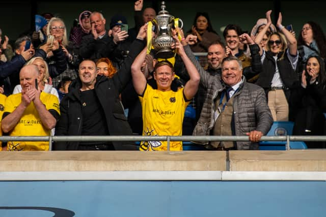 Skipper Dean Holden holding aloft the trophy won by the Legends at the 2022 Manchester Remembers match