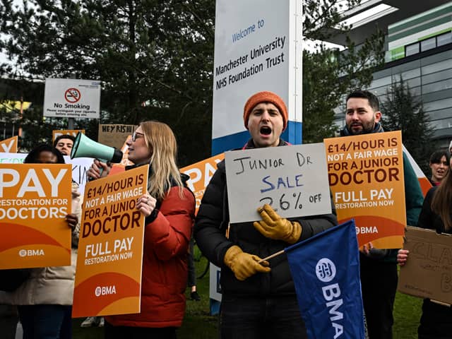 Demonstrators hold placards as they take part in a protest by junior doctors, amid a dispute with the government over pay, outside of Saint Mary's Hospital, in Manchester, on March 15, 2023. 