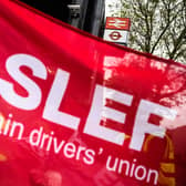 A group of rail workers are seen through a ASLEF union flag. Credit: Leon Neal/Getty Images.