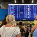Tourists stand in front of an information board at the airport's departure hall as evacuations are underway due to wildfires, on the Greek island of Rhodes on July 23, 2023. Locals and tourists fled hotspots on Rhodes, as firefighters battled a blaze that had sparked the country's largest-ever fire evacuation. Firefighters were bracing for high winds that have been forecast for the afternoon and that could hamper their efforts. (Photo by Will VASSILOPOULOS / AFP) (Photo by WILL VASSILOPOULOS/AFP via Getty Images)