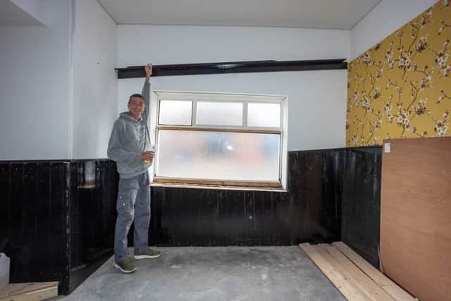 Carl Falconer  standing next to the shelf where pool balls roll up instead of down.  