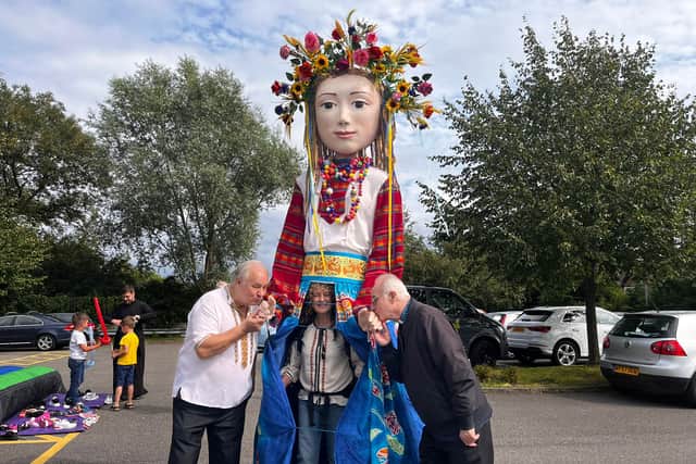 Bob Sopel (L) and Father Yevhen Nebesniak (R) pose with Sofia the puppet,  controlled by Melanie Roberts of Global Grooves, on Ukrainian Independence Day at the Dnipro cultural centre in Cheetham Hill.