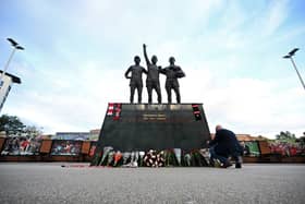 Manchester United fans lay floral tributes at the Holy Trinity statue outside Old Trafford.