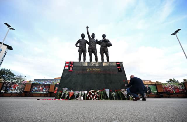 Manchester United fans lay floral tributes at the Holy Trinity statue outside Old Trafford.