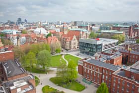 Aerial view of the University campus, showing Gilbert square, the modern architecture of the Learning Commons beside grand old buildings such as Whitwoth Hall and the tower. Manchester skyline in the background