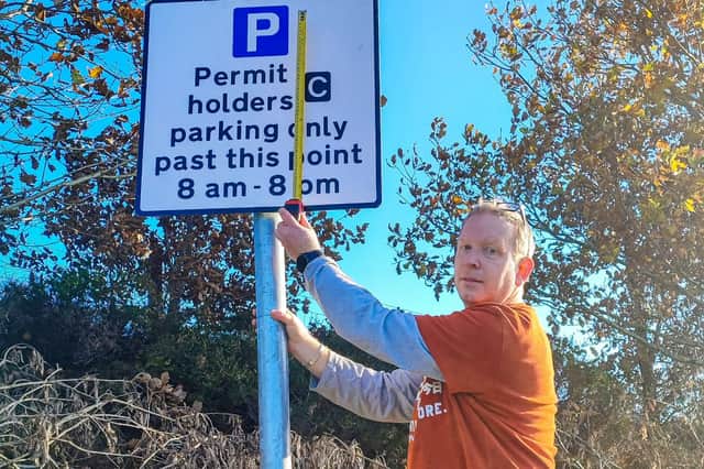 Chris Burton measuring permit holders sign, after finding the 'blue P' was 6cm short of 20cm requirement.