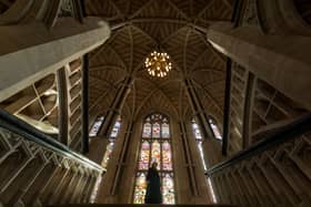 Communications officer, Jenny Francis, stands at the top of the grand staircase with the restored stained glass windows behind her. 
